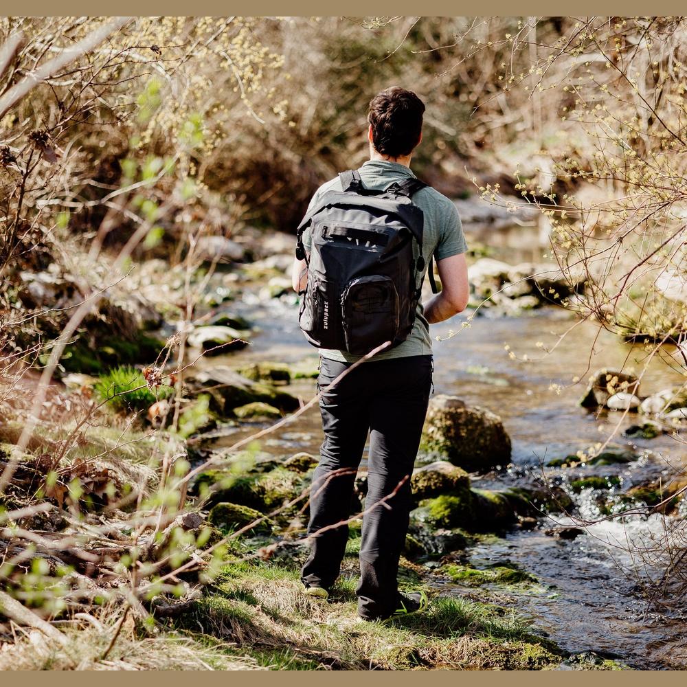 Sac à dos étanche Nomad 35 porté en extérieur près d'un cours d'eau